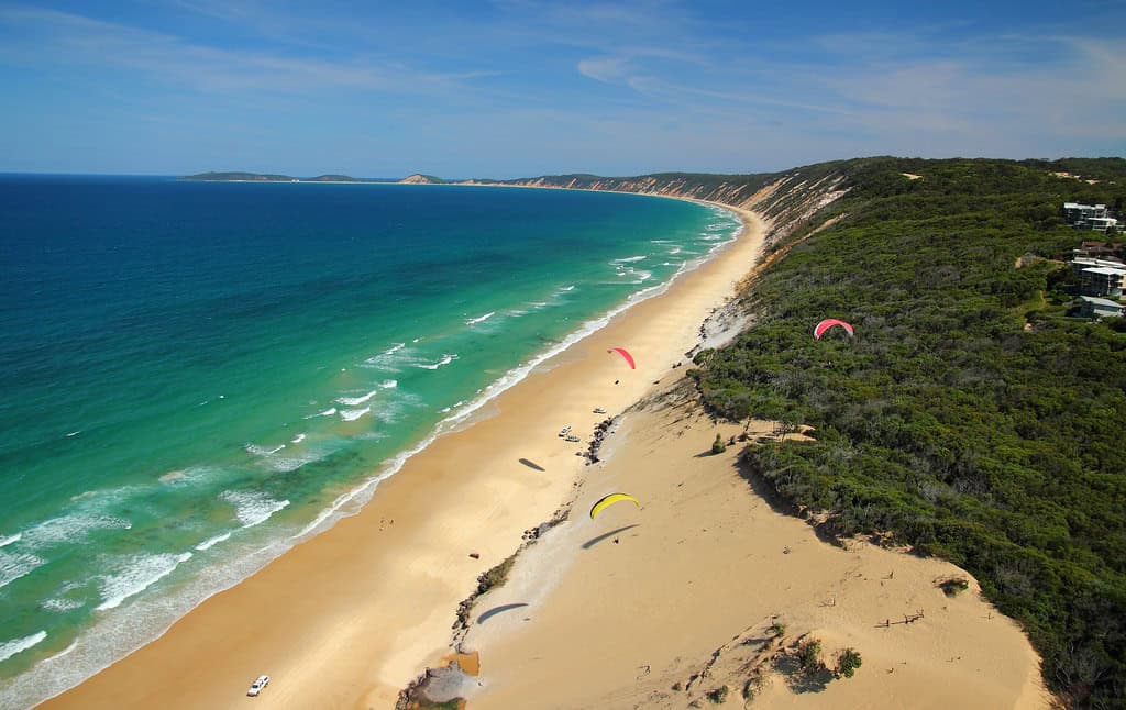 Arial image of Rainbow Beach with red hang gliders