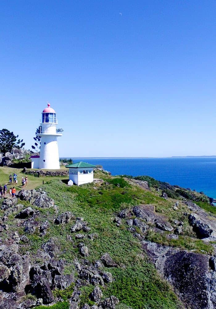 An image of Double Island Point Lighthouse with a blue sky and green grass