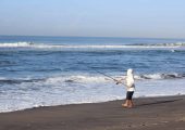 A man fishing on the edge of Rainbow Beach