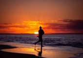 A silhouette of a fisherman fishing at Rainbow Beach